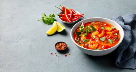 Soup Tom Yum with prawns in a grey bowl. Grey background. Close up. Copy space.