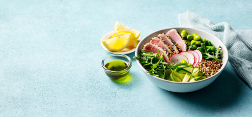 Healthy salad. Tuna, cucumber, green beans, arugula and quinoa. Buddha bowl. Blue background. Copy space.
