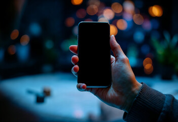 Smartphone in hands at night, bokeh effect and blurred light.