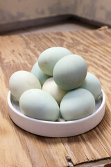 A Collection of Pastel-Colored Eggs in a White Bowl on a Rustic Wooden Surface