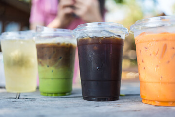 Many of summer drink in clear plastic cup, close up view on wood table. Refreshing summer