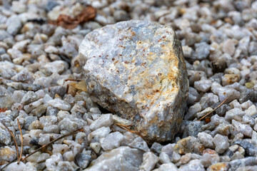 Close-up of a textured stone surrounded by gravel, showcasing natural colors and patterns. Perfect for backgrounds, geology, or nature themes.