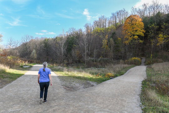 Rear view of a mature woman taking the left fork on a footpath, Ontario, Canada