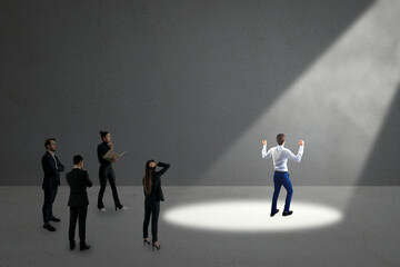 Fototapeta premium Businessperson in spotlight while others observe, symbolizing career choice and ambition on a gray background.