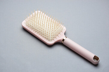 Hair comb with a pink handle on a gray background.
