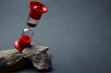 Hourglass close-up on a black background. Sea stones and wood.