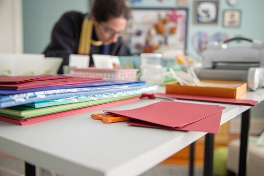 Woman sitting at a table making homemade cards in a studio
