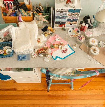 Overhead view of assorted fabrics, tools and craft objects on a table in a studio