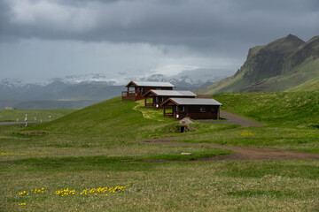 Grey sky over a Row of three traditional wooden cabins in rural landscape, Iceland
