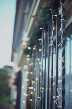 Close-up of illuminated string lights hanging on the outside of a house in front of a window