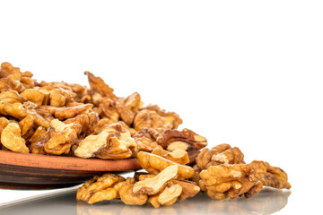 Shelled walnuts on a clay plate, close-up, isolated on a white background.