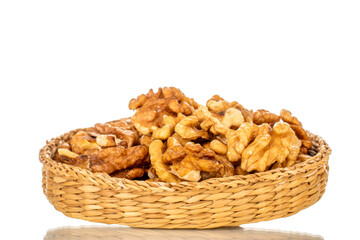 Shelled walnuts in a straw plate, close-up, isolated on a white background.