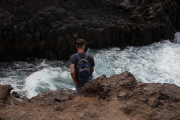 Ein Mann mit Rucksack beobachtet die Wasserwellen
