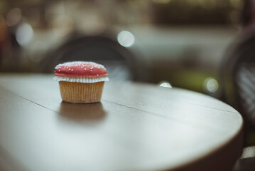 Close-up of a Cupcake on a table with red icing and sprinkles made to look like a mushroom