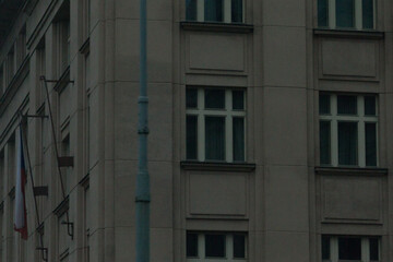 The exterior of a building displays a series of windows and various flags within a bustling urban environment, showcasing city life