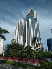 group of tall buildings seen from below, with blue sky in the background and a pedestrian walkway at the bottom