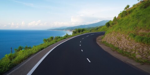 A road with a beautiful ocean view in the background. The road is empty and straight. The ocean is calm and blue
