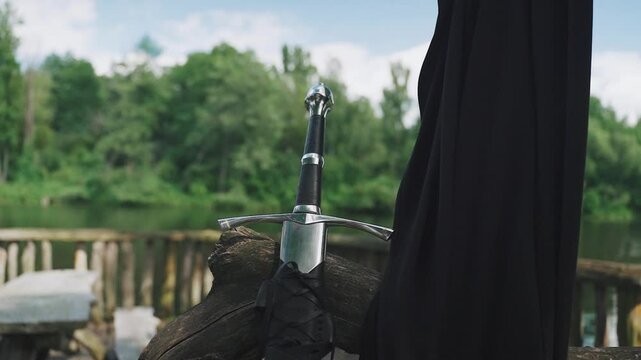 Medieval steel Viking sword, close-up. Handle of ancient sword in leather sheath on wooden ship. Cold weapons of crusader times, knightly battles, conquest campaigns. Warrior's weapon for knife fight