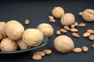 Plate full of walnut and almonds in black blackground