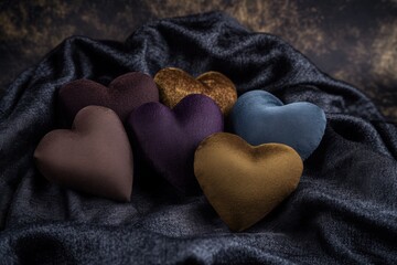 Fototapeta premium Colorful fabric hearts on dark velvet background in various shades