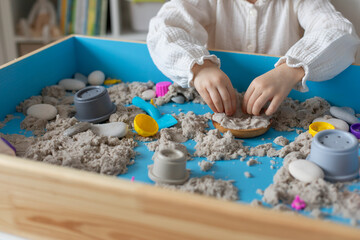 Children activity with kinetic sand for motor and sensory development. Toddler play therapy with colorful toys on sandbox..