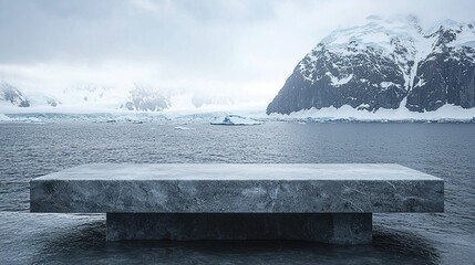 Empty stone platform overlooking icy Antarctic ocean and snowy mountains.