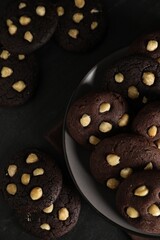 Tasty chocolate cookies with hazelnuts on black table, flat lay