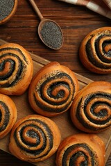 Tasty buns with poppy seeds on wooden table, flat lay