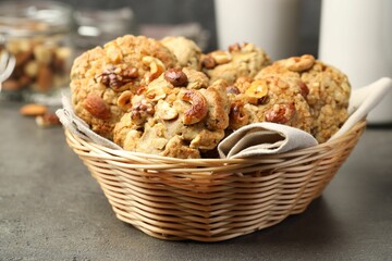 Tasty cookies with nuts in wicker basket on grey table, closeup