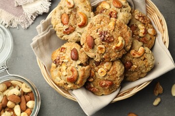 Tasty cookies with nuts in wicker basket on grey table, top view