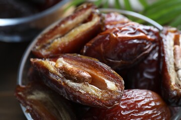 Many tasty dried dates in bowl on table, closeup