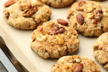 Tasty cookies with nuts in baking tray, closeup