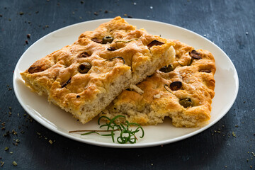 Focaccia alle olive - foccacia with green olives, garlic and rosemary on black background