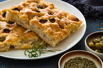 Focaccia alle olive - foccacia with green olives, garlic and rosemary on black background