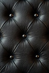 Naklejka premium Close-up of black leather upholstery with button tufting, showcasing luxury and elegance for interior design and furniture.