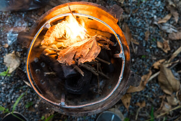 Dry leaf in stove igniting barbeque fire. Top view