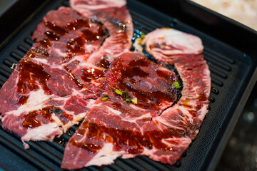 Premium rare slices of fine beef on a black tray ready to grill. Delicious grilled