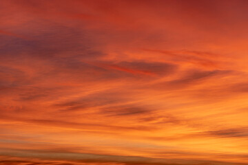 Stunning sunset sky. The sky is painted with vibrant shades of orange, pink, and purple, creating a picturesque and dramatic view. Horizontal clouds add texture and depth to the scene