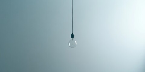 A single light bulb hanging from the ceiling against a soft blue background, showcasing minimalist interior design.