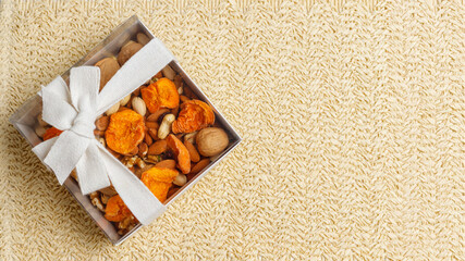 Dried fruits and nuts in a gift box on a straw background . Concept of the Jewish holiday Tu Bishvat. Copy space