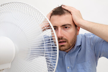 Flushed man feeling hot in front of a fan