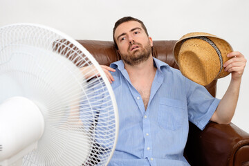 Flushed man feeling hot in front of a fan