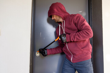 Burglar trying to force a door lock using a crowbar