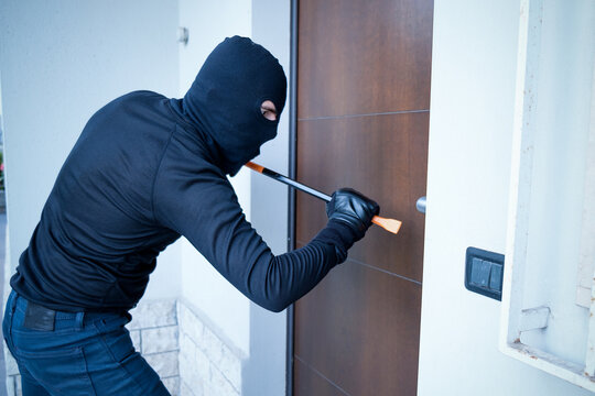 Burglar trying to force a door lock using a crowbar