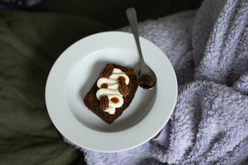 plate in hands with carrot cake with pecans and cream, top view