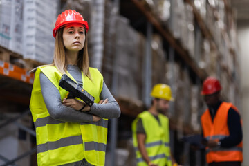 Young female warehouse worker in safety gear holding a barcode scanner