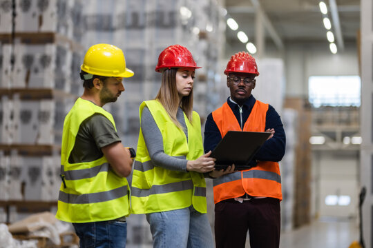 Warehouse team discussing logistics with a tablet in industrial setting