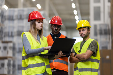 Team of warehouse workers reviewing inventory data on a laptop computer