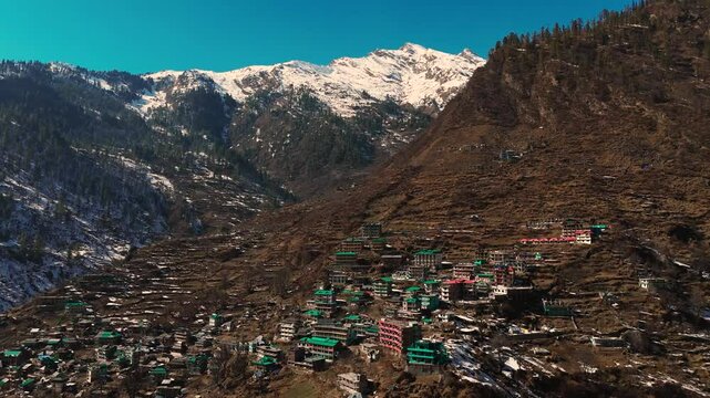Drone shot of a small town Tosh in Himachal Pradesh on a dried snow-covered hill in India