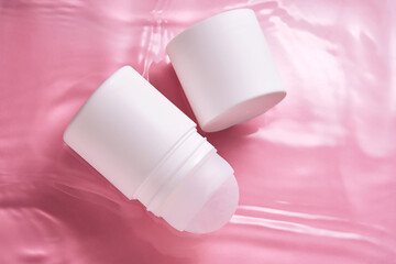 Roll-on deodorant on a pink background in water.